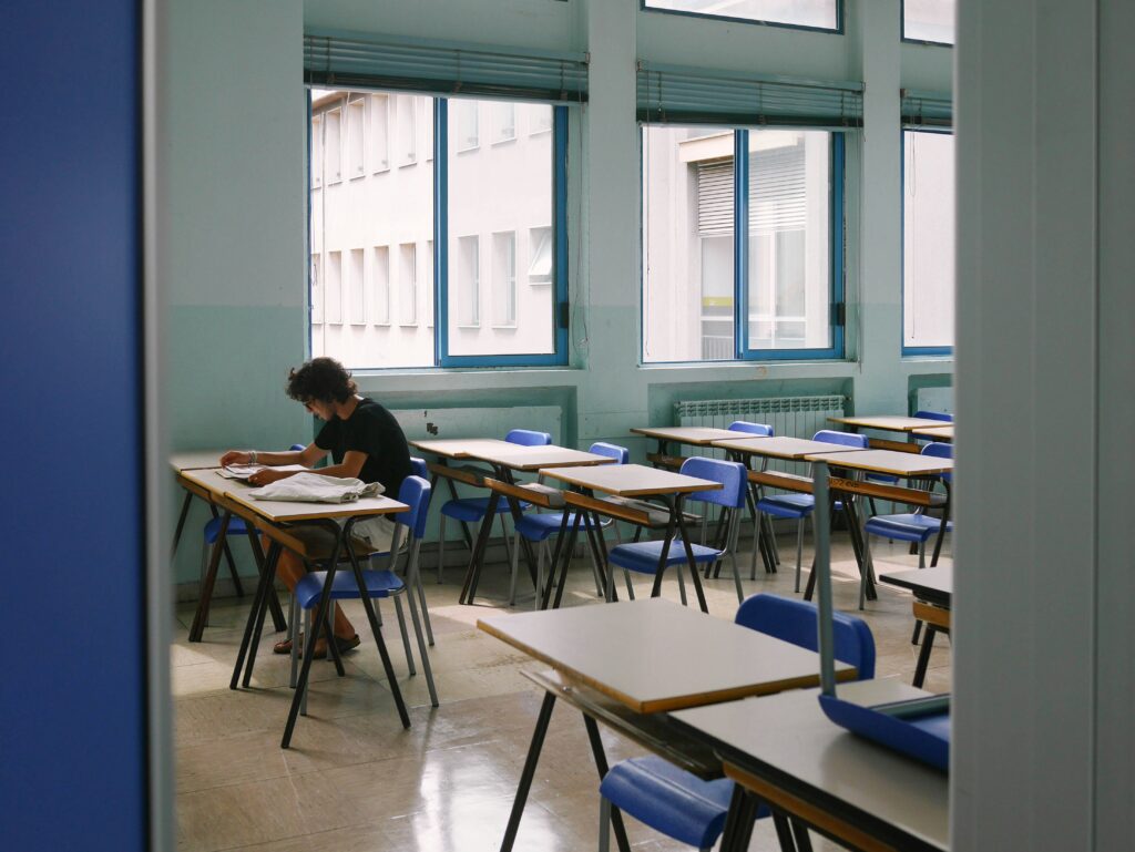 Schoollokaal met blauwe stoelen en een man die aan het lezen is - schoolventilatie - Lucht & Ventilatie