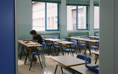 Schoollokaal met blauwe stoelen en een man die aan het lezen is - schoolventilatie - Lucht & Ventilatie